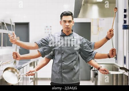 Alles, was ein Koch braucht. Digital verändertes Porträt eines Küchenchefs, der verschiedene Kochutensilien in seiner Küche hält. Stockfoto