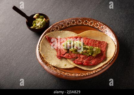 Tacos de Cecina Enchilada con Guacamole. Gesalzenes, sonnengetrocknetes Schweinefleisch oder Rindfleisch, gewürzt mit verschiedenen Gewürzen und Chilischoten, in der Regel in Tacos gegessen Stockfoto