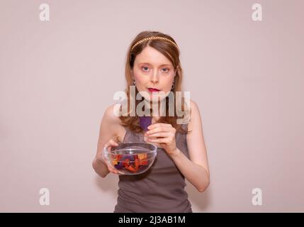 Junge schöne Frau hält bunte Kartoffelchips in Glas transparente Schüssel Stockfoto