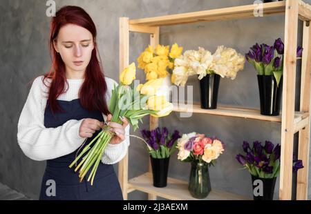 Europäisches Blumengeschäft Konzept. Eine weibliche Floristin kreiert einen schönen Strauß aus Frühlingsblumen. Schönes frisches Bouquet. Bildung, Meisterkurse Stockfoto