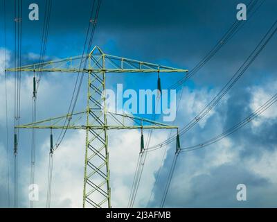 Stromleitung mit Pylon gegen dramatischen Himmel, Nahaufnahme. Konzept für erneuerbare Energien. Energiekrise und steigende Strompreise. Stockfoto