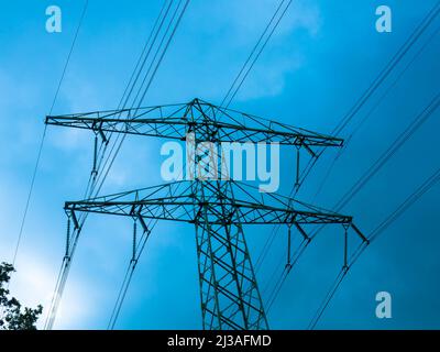 Stromleitung mit Pylon gegen dramatischen Himmel, Nahaufnahme. Konzept für erneuerbare Energien. Energiekrise und steigende Strompreise. Stockfoto