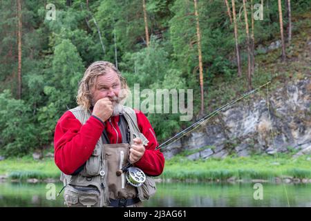 Reifen Fliegenfischen Fischer nimmt Fliegen für Angelrute Ausrüstung. Machen Sie bereit Angeln Stockfoto