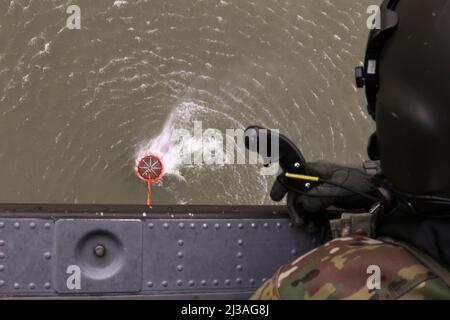 Sgt. 1. Klasse Kyle Moyer, ein UH-60m Black Hawk Helikopter-Crew-Chef und Instruktor am Eastern Army National Guard Aviation Training Site (EAATS), sagt dem Piloten, wo er den Wassereimer während des Trainings am 5. April in Fort Indiantown Gap führen soll. Diese gemeinsame Schulung zwischen EAATS und den Feuerwehrmannschaften von Conservation Wildland verbessert ihre Fähigkeit, Wassereimer als Ressource für Waldbrände oder verschriebene Verbrennungen zu verwenden. (USA Foto der Armee-Nationalgarde von Staff Sgt. Zane Craig) Stockfoto