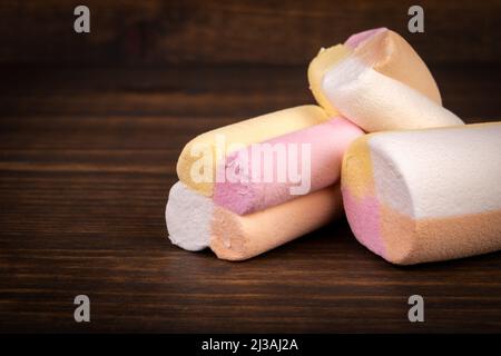 Süßigkeiten, bunte Marschwalben auf dunklem Holzhintergrund. Stockfoto