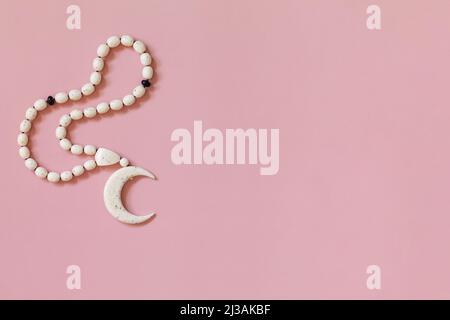 Ramadan Kareem Grußkarte, Einladung. Islamische Rosenkranz-Perlen des Ramadan auf hellrosa Hintergrund. Draufsicht flach liegend. Speicherplatz kopieren. Stockfoto