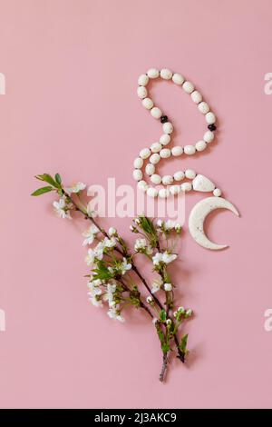 Ramadan Kareem Grußkarte, Einladung. Islamische Rosenkranz-Perlen und weiße Blumen auf hellrosa Hintergrund. Draufsicht flach liegend. Stockfoto