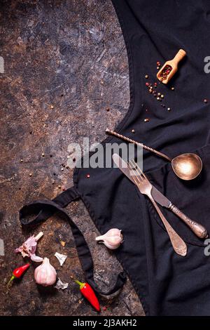 Draufsicht auf Knoblauchzehen und rote Chilischoten mit Vintage-Metallbesteck auf Steinhintergrund, Nahaufnahme mit Platz für Text Stockfoto