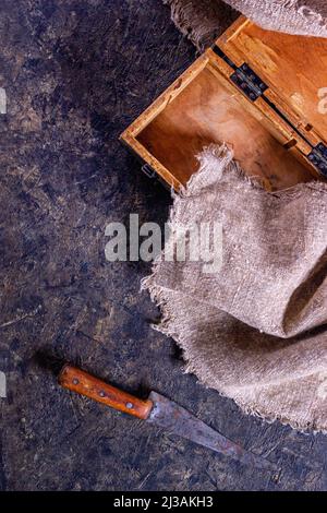 Vintage Metzgermesser und alte Holzkiste auf Steinküchenoberfläche. Draufsicht mit selektivem Fokus Stockfoto