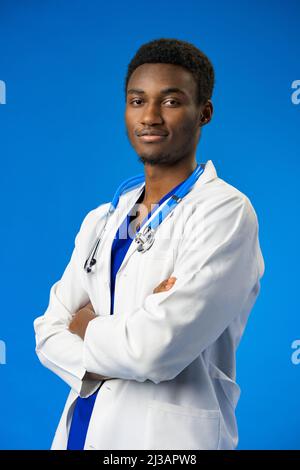 Selbstbewusster schwarzer Arzt posiert über blauem Studiohintergrund. Stockfoto