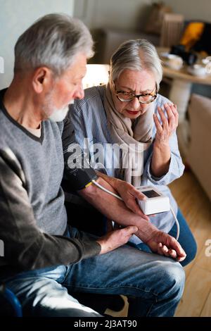 Seniorenpaar zu Hause, das den Blutdruck misst. Home Monitoring People Healthcare Konzept Stockfoto