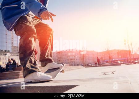 Mann junge Skateboarder Beine Skateboarding Skatepark bei Sonnenuntergang. Konzept Tricks und springen auf Skateboard. Stockfoto