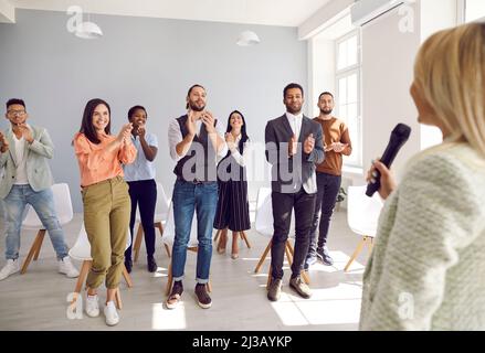 Glückliche, dankbare Menschen applaudieren Sprecherin, die mit ihnen seine Erfahrungen und sein Wissen teilte. Stockfoto