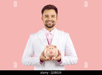 Lächelnder Mann hält Sparschwein, um Geld zu sparen Stockfoto