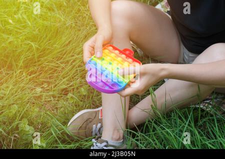 Nicht erkennbare Frau, die in der Natur mit einem Pop-it-Spielzeug spielt Stockfoto