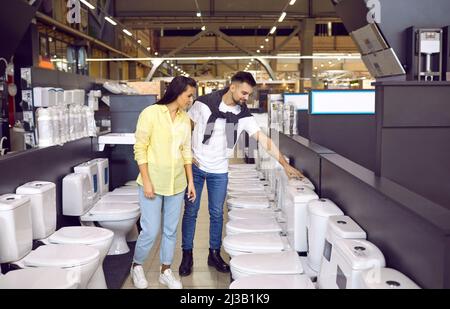 Junges Paar, das sich die Spültoiletten in einem modernen Baumarkt oder Einkaufszentrum ansieht Stockfoto
