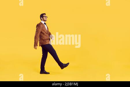 Lustiger schwarzer Mann in einer Leopardenjacke, der auf einem gelben Copy Space Studio-Hintergrund läuft Stockfoto