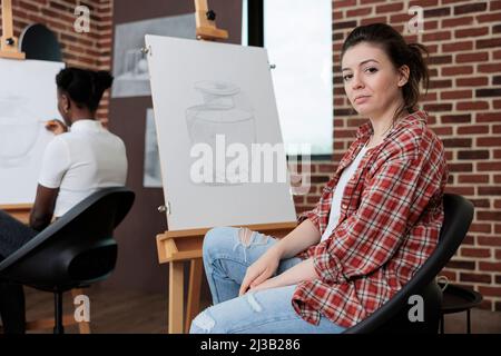 Portrait eines lächelnden Studenten, der an einem künstlerischen Meisterwerk arbeitet, Zeichnung, Vase-Modell auf dem Gemälde, Canvad, der in der grafischen Technik mit Zeichenwerkzeugen im Kreativitätsstudio arbeitet. Art Class Konzept Stockfoto