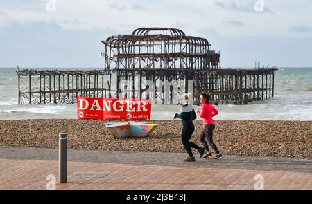 Brighton UK 7. April 2022 - Läufer kommen an einem stürmischen Tag am West Pier in Brighton vorbei, nach einer Nacht starker Winde und Regen an der Südküste : Credit Simon Dack / Alamy Live News Stockfoto