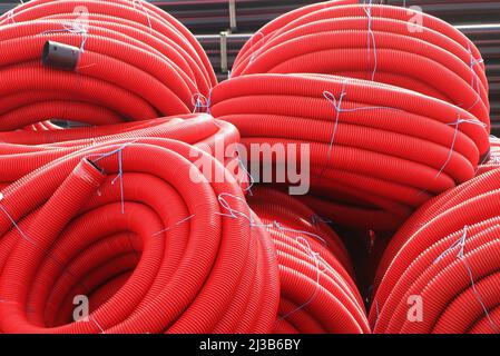 Gruppe von aufgerollten roten Kabelschutzrohren, industrieller Hintergrund Stockfoto