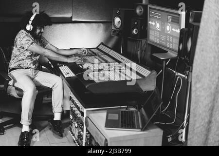 Afrikanischer Musikproduzent mischt neues Musikalbum im Boutique-Studio - Fokus auf der rechten Hand - Schwarz-Weiß-Schnitt Stockfoto