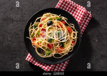 Spaghetti mit Gemüse (Brokkoli, Tomaten, Paprika) auf schwarzem Hintergrund Stockfoto