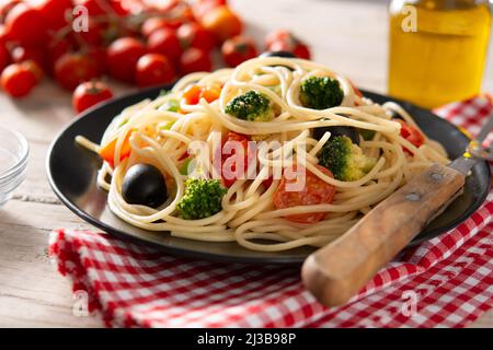Spaghetti mit Gemüse (Brokkoli, Tomaten, Paprika) auf Holztisch Stockfoto