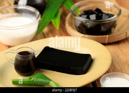 Cincau Hitam oder Schwarzgras-Gelee in Stücke pudding, gesunde Ernährung. Vorbereitung von Takjil für Buka Puasa Ramadhan mit Kokosöl Santan und Palm Sugar S Stockfoto