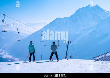 Skifahrer, die im Winterresort auf den schneebedeckten Hang am Berg gleiten Stockfoto