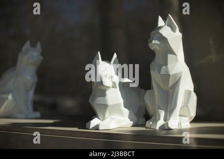 Kubische Figuren von Katzen. Skulptur der weißen Katze. Inneneinrichtung. Licht fällt auf ein Objekt aus Kunststoff. Stockfoto