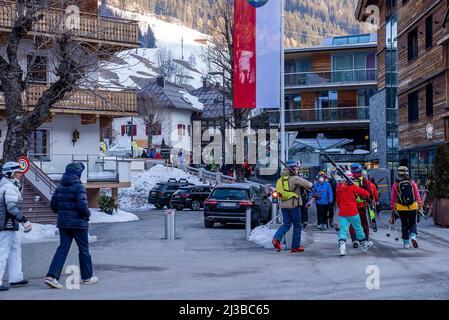 Leute in Skibekleidung laufen durch die Straße neben dem Chalet im Winterresort Stockfoto