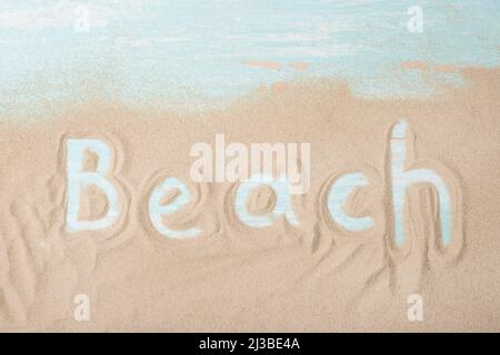 Die Inschrift des Strandes auf den Brettern mit Sand Stockfoto