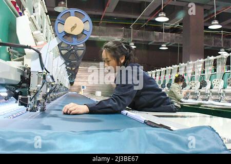 QIANDONGNAN, CHINA - PARIL 7, 2022 - in einer Werkstatt in Qiandongnan Miao und Dong Autonomous Pref arbeiten Frauen aus der Region an einer Polyester-Nähanlage Stockfoto