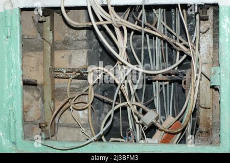 Elektrische Netze und Sicherheitskonzept - Elektrotafel mit verflochtenen Drähten in einem russischen Wohngebäude. Stockfoto