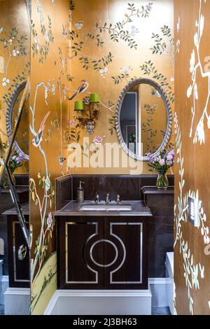 Gold Chinoiserie de Gournay Tapete mit ovalem Spiegel über Waschbecken in Holland Park Home, London, UK Stockfoto