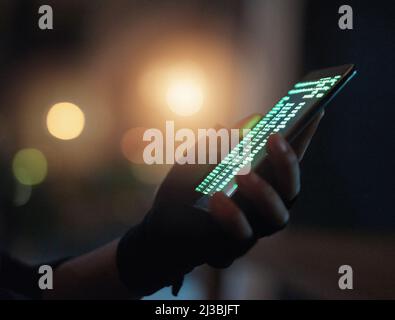 Schützen Sie sich vor Betrügern. Aufnahme eines nicht erkennbaren Hackers, der im Dunkeln ein Handy benutzt. Stockfoto