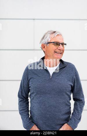 Lächelnder älterer Mann in grauem Pullover Stockfoto