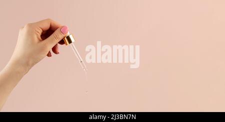 Aus der Pipette, die auf dem Stein liegt, fließt ein Tropfen Serum für die Haut. Stockfoto