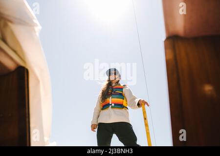 Lächelnde Frau, die gegen den blauen Himmel steht Stockfoto