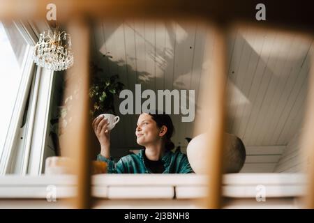 Junge Frau trinkt Kaffee zu Hause Stockfoto