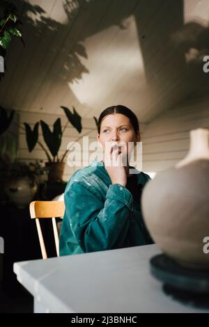 Frau sitzt am Tisch zu Hause Stockfoto