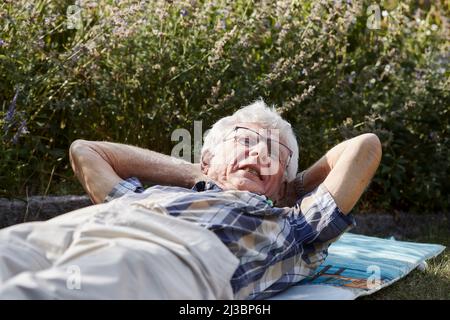 Älterer Mann, der auf dem Rasen liegt Stockfoto