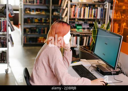 Studentin mit Computer in der Bibliothek Stockfoto