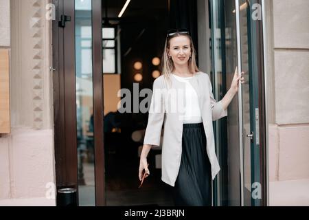 Attraktive junge Frau, die aus einem kleinen Café kommt. Stockfoto