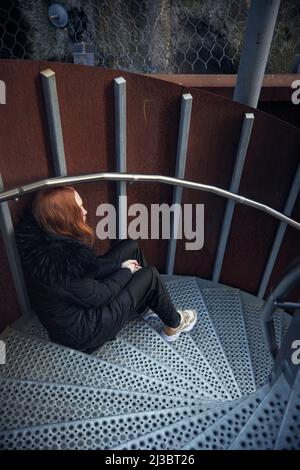 Junge Frau sitzt auf der Treppe Stockfoto