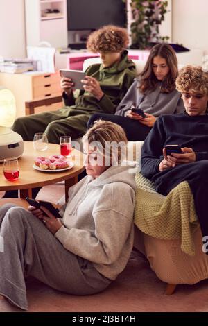 Mutter und Kinder, die zu Hause elektronische Geräte benutzen Stockfoto