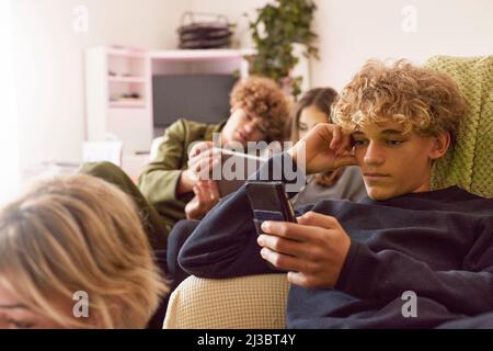 Geschwister, die zu Hause elektronische Geräte verwenden Stockfoto