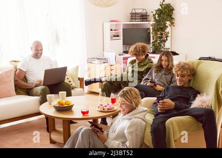Familie mit Kindern, die zu Hause elektronische Geräte verwenden Stockfoto