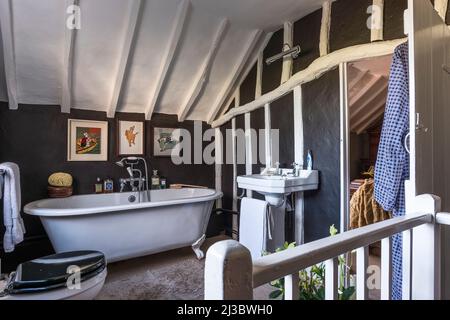 Freistehende Badewanne und schwarze Wände im Dachgeschoss Badezimmer von 18. Jahrhundert Suffolk Cottage, Großbritannien Stockfoto