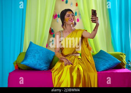 Indische Braut nimmt Selfie mit Smartphone auf haldi Zeremonie Stockfoto